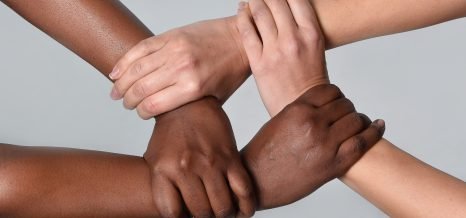 white Caucasian female hands and black African American holding together in world unity and racial love and understanding in tolerance and races diversity cooperation concept